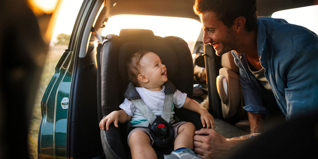 Pai e filho sorridentes em carro seguro